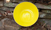 Yellow glass bowl handblown in the USA nestled on a stone wall. Made in the USA from Serve Kindness.